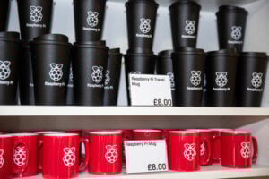 A shelf of Raspberry Pi-branded Travel mugs and ceramic mugs
