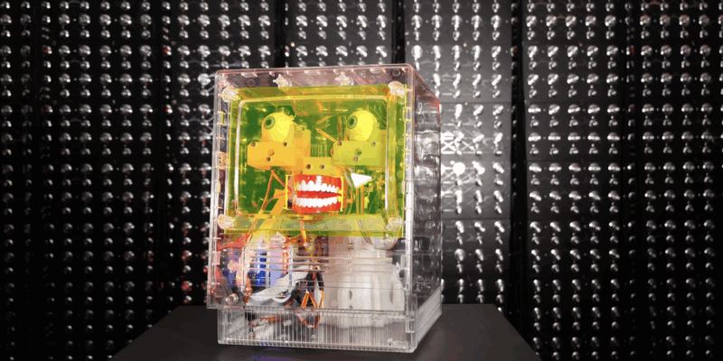 furby facial recognition robot in a clear case in front of a dark background