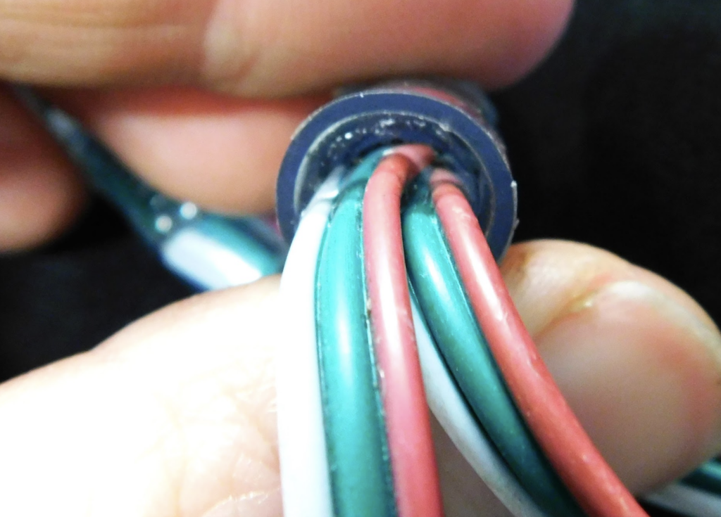 looking down the barrel of a thick wire casing full of green and red and white wires