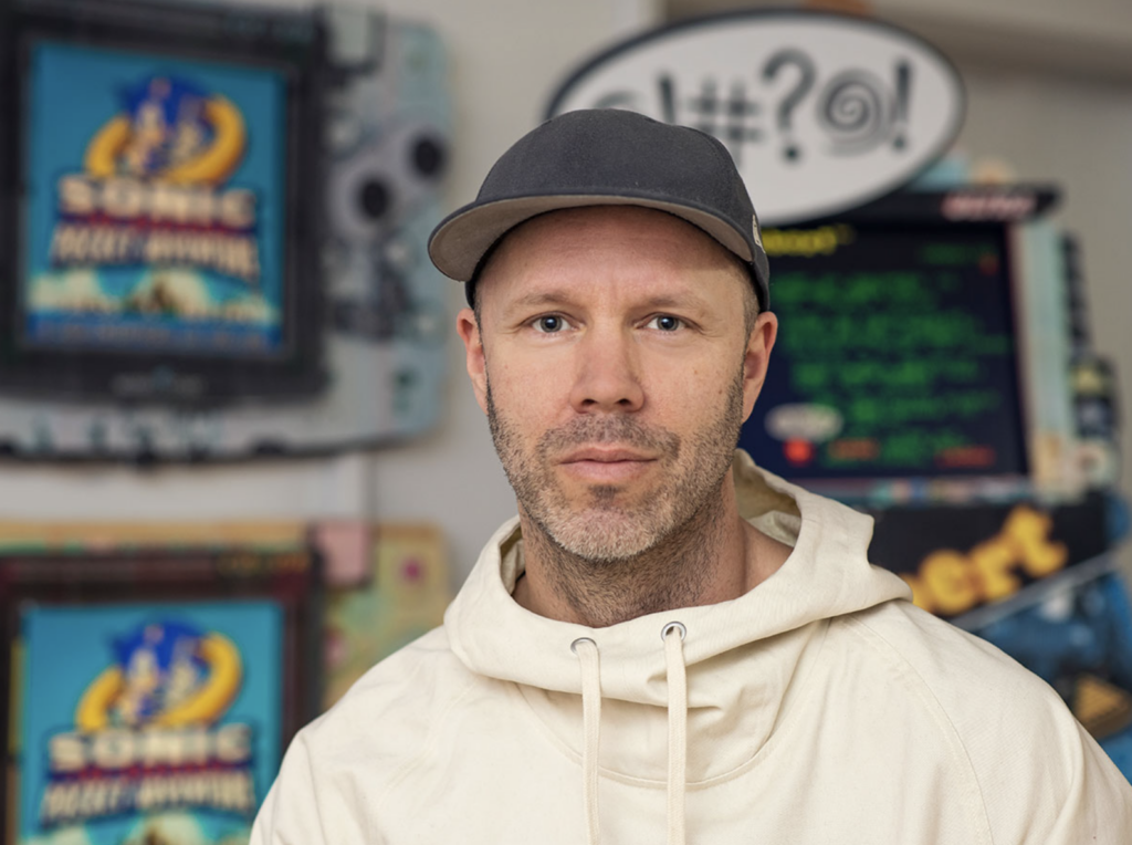 the maker connor in a cream hoodie and grey baseball cap