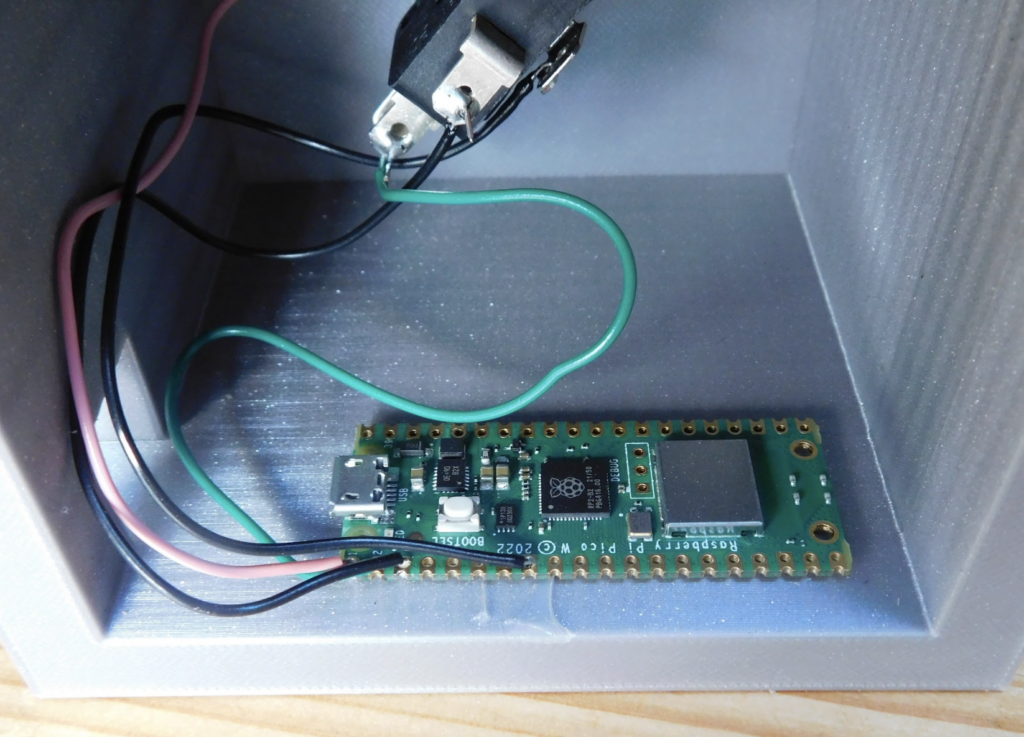 a raspberry pi board housed within a light blue box, which could be 3D printed. Here are the details based on the image:

Circuit Board: The main component is a green electronic circuit board with various electronic elements mounted on it.
Wires: There are wires in black, red, and green connected to the circuit board, likely for power and signal transmission.
Connectors: A black clip connector is attached to the wires, indicating the board may interface with other devices or systems.
Enclosure: The circuit board is placed inside a light blue box, which has a layered texture typical of 3D printed objects.
The image doesn’t specify the exact purpose of the circuit board assembly, but it’s common in DIY electronics and could be part of a larger project or device. The components and connections visible are typical of hobbyist or prototyping work in electronics.