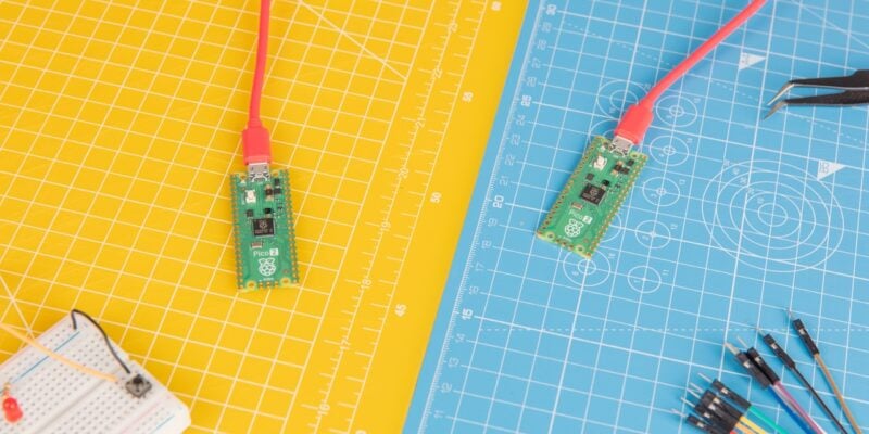 two raspberry pi pico 2 boards on a yellow and a blue cutting board. both are connected via usb c with raspberry red cables